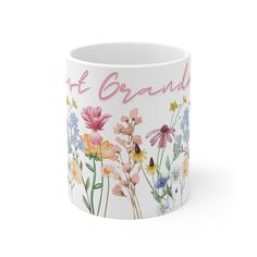 a white coffee mug with flowers painted on the side and pink lettering that says,'not