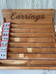 a wooden sign that says carings and six pairs of earring holders in front of it