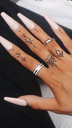 two hands with different tattoos and rings on them