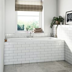 a white bathroom with two sinks, toilet and bathtub in the middle of it