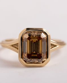 a fancy yellow gold ring with an orange and brown diamond in it's center