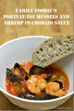 a white bowl filled with shrimp and mussels next to a piece of bread