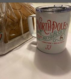 a white coffee mug sitting on top of a table next to a loaf of bread