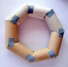 an origami wreath made out of toilet paper with blue strips on it, sitting on a white surface