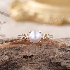 a pearl and diamond ring sitting on top of a piece of wood