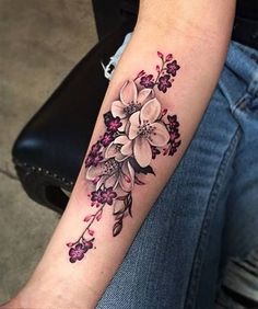 a woman's arm with flowers on it, and the tattoo is done in black ink