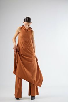 This dress,crafted from high-quality knit fabric,offers a fluid and graceful silhouette that flatters all body types.The sleeveless design is ideal for layering,allowing you to transition effortlessly from season to season.The standout feature of this dress is its unique cowl neckline,adding a touch of contemporary flair to a classic piece.The asymmetrical hemline creates a dynamic visual effect,ensuring you stand out in any crowd.The diagonal seam lines not only enhance the dress's aesthetic appeal but also contribute to its structured fit.Ideal for casual outings or semi-formal events,this terracotta midi dress is versatile enough to be dressed up or down.Pair it with sandals for a relaxed daytime look or with heels and statement jewelry for an evening ensemble.