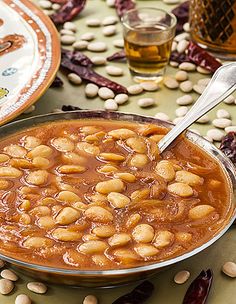 a bowl filled with beans and sauce next to two plates full of beans on the table