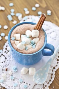 hot chocolate with marshmallows and cinnamon in a blue mug on a doily