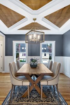 a dining room with a wooden table surrounded by beige chairs and an area rug on the floor