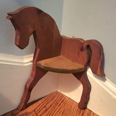 a wooden horse shaped chair sitting on top of a hard wood floor