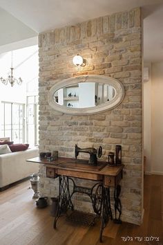 a sewing machine is sitting on a table in front of a brick wall with a round mirror above it