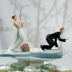 a wedding cake topper with a bride and groom on it, holding a fishing rod