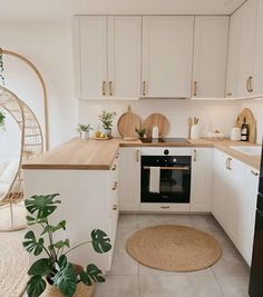 a kitchen with white cabinets and wooden counter tops, potted plants on the floor