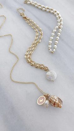 A long necklace featuring a natural seashell painted with gold, a freshwater pearl, and a gold coin metal featuring either a heart, moon or a hamsa. Beautiful, part of our pearl of wisdom collection, this necklace is a summer essential. Gold Charm Necklace For Vacation, Gold Charm Necklaces For Vacation, Gold Shell-shaped Jewelry With Pearl Charm, Ocean-inspired Gold Shell Charm Necklace, Gold Pearl Shell Necklace For Beach, Gold Pearl Necklace With Pearl Charm For Beach, Gold Shell Jewelry With Pearl Chain, Gold Shell Necklace With Pearl Chain, Gold Charm Necklace With Pearl Pendant For Beach