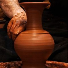 a man is making a vase on a potter's wheel with one hand and the other