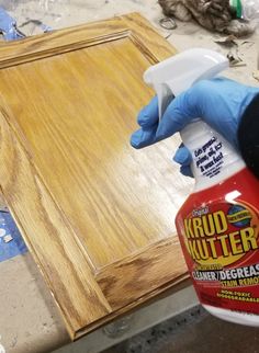 a person in blue gloves and rubber gloves sprays wood glue on a piece of plywood