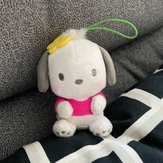 a small stuffed animal sitting on top of a black and white striped couch pillow with a yellow ribbon around it's neck