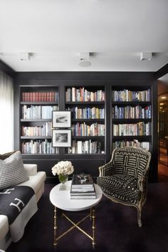 a living room filled with furniture and lots of bookshelves covered in black bookcases