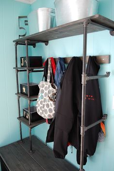 a shelf with clothes and bags on it in a room that has blue painted walls