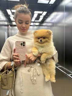 a woman holding a small dog in her arms and looking at the phone case she is holding