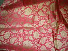 a red and gold brocaded fabric with large flowers on the bottom half of it