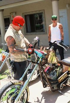 two men standing next to each other in front of a motorcycle