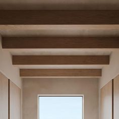 an empty room with wooden floors and white walls, looking out onto the ocean from inside