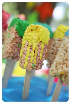 rice krispy treats are on sticks with yellow frosting