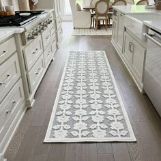 a kitchen with white cabinets and an area rug on the floor in front of the stove