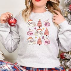 Get into the holiday spirit with our Groovy Santa Pink Christmas and Holiday Drink T-Shirt, Sweatshirt, or Hoodie. Featuring a groovy Santa and festive holiday drink design, this top is perfect for adding some fun to your wardrobe. Available in three styles - t-shirt, sweatshirt or hoodie - you can choose the fit that suits you best. Spread some cheer this season with our Groovy Santa Pink Christmas and Holiday Drink top. Key Features: - Festive Groovy Santa design - Fun holiday drink graphic - Available in t-shirt, sweatshirt or hoodie styles  Whether you're looking for a cozy sweatshirt to snuggle up in on cold winter nights or a casual t-shirt that expresses your festive spirit at any time of day, we've got you covered. The pink color adds an extra touch of whimsy to this jolly design. Festive Cozy Crew Neck Sweater, Casual Festive Sweatshirt For Fall, Cozy Crew Neck Sweater For Holiday, Casual Fall Festive Sweatshirt, Casual Long Sleeve Hoodie For Holiday, Casual Long Sleeve Holiday Hoodie, Cozy Winter Holiday Sweatshirt, Festive Long Sleeve Cotton Sweater, Festive Long Sleeve Fall Sweatshirt