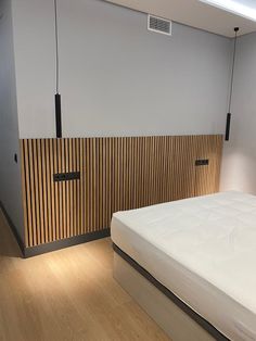 a white bed sitting in a bedroom next to a wooden paneled wall and floor