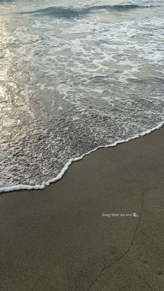 an ocean beach with waves coming in to shore and the sun reflecting on the sand