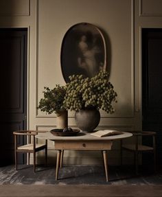 a table with some flowers on it in front of a mirror and two stools