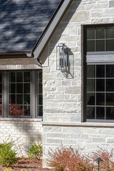 a white brick house with two windows and a light fixture on the side of it