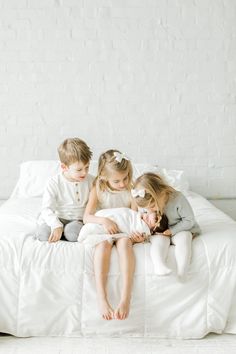 three children are sitting on a bed together