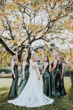 the bride and her bridesmaids pose for a photo in front of a tree