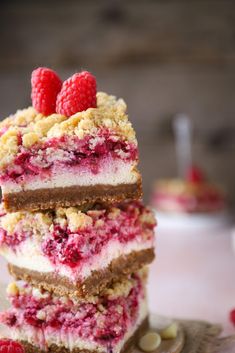 raspberry cheesecake bars stacked on top of each other with two raspberries