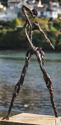 a sculpture is standing in front of a body of water