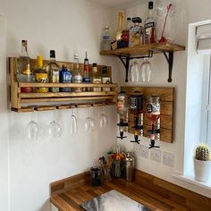 a wooden counter topped with lots of bottles and glasses next to a wine glass rack