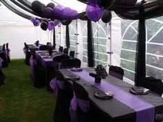 tables set up with purple and black decorations in a tented area for an event