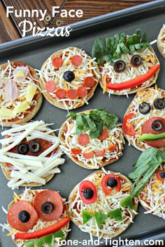 pizzas with eyes, cheese and vegetables on a baking sheet for an easy kids'snack