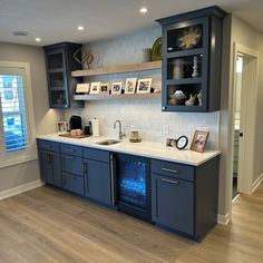 an empty kitchen with blue cabinets and white counter tops is pictured in this image, there are pictures on the shelves above the sink