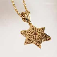 Elevate your personal style with our exquisite Gold-Plated Star of David Pendant, a symbol of faith and cultural significance. This pendant beautifully captures the essence of the Star of David, adorned with a captivating garnet or stone at its center, adding a touch of elegance and meaning to your jewelry collection. Measuring a graceful 1.8 inches (45 mm) in length and 0.8 inches (20 mm) in width, this pendant boasts intricate craftsmanship that showcases the star's delicate interlocking trian Elegant Star Of David Gemstone Necklace, Spiritual Star-shaped Gemstone Jewelry, Elegant Star Of David Birthstone Jewelry, Elegant Star Of David Hallmarked Necklace, Elegant Birthstone Necklace With Star Of David, Gold Star Of David Gemstone Jewelry, Gold Star Of David Jewelry With Gemstone, The Star Of David, Star Of David Necklace