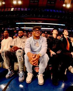 a group of men sitting on top of a blue floor in front of a crowd