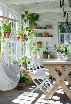 a white hammock sitting on top of a wooden table next to potted plants