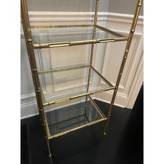 a gold metal shelf with glass shelves on top