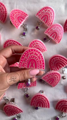 a woman's hand is holding up some pink paper hearts with designs on them