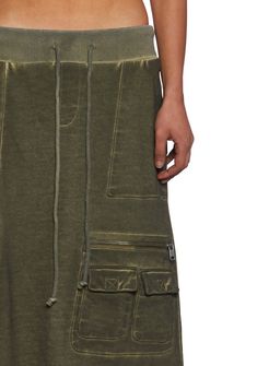 in a French terry cloth construction with a washed finish. With a ribbed waistline, a waistband with adjustable tie closures, side pockets, 1 front zippered cargo pocket with 2 pockets with velcro closures, 1 front pocket with velcro closure and zippered detail, 2 back pockets with velcro closures and zippered details, a distressed raw hem, and Darker Wavs printed logo on the back. Maxi Cargo Skirt, Cargo Skirt, Skirt With Pockets, Cargo Pocket, Green Skirt, Skirts With Pockets, Goth Fashion, Terry Cloth, Print Logo