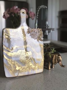 an elephant figurine sitting on top of a counter next to a glass cutting board